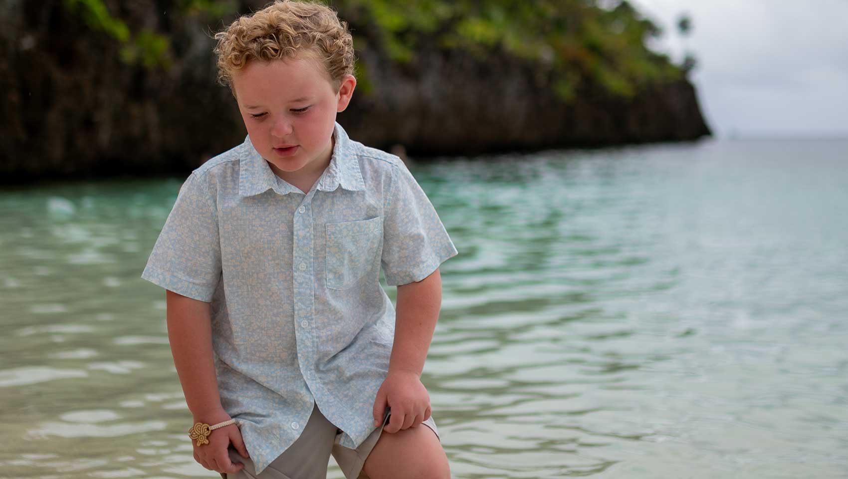 boy walking in water on beach