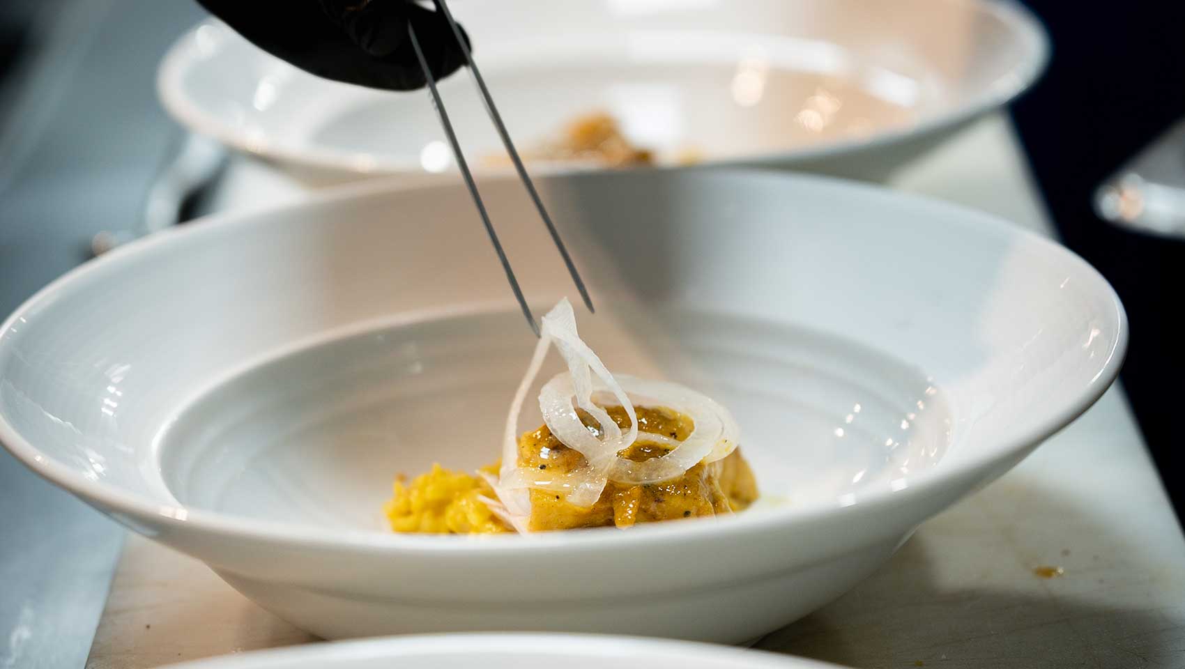 Chef wears gloves to garnish dish at Kimpton Grand Roatan