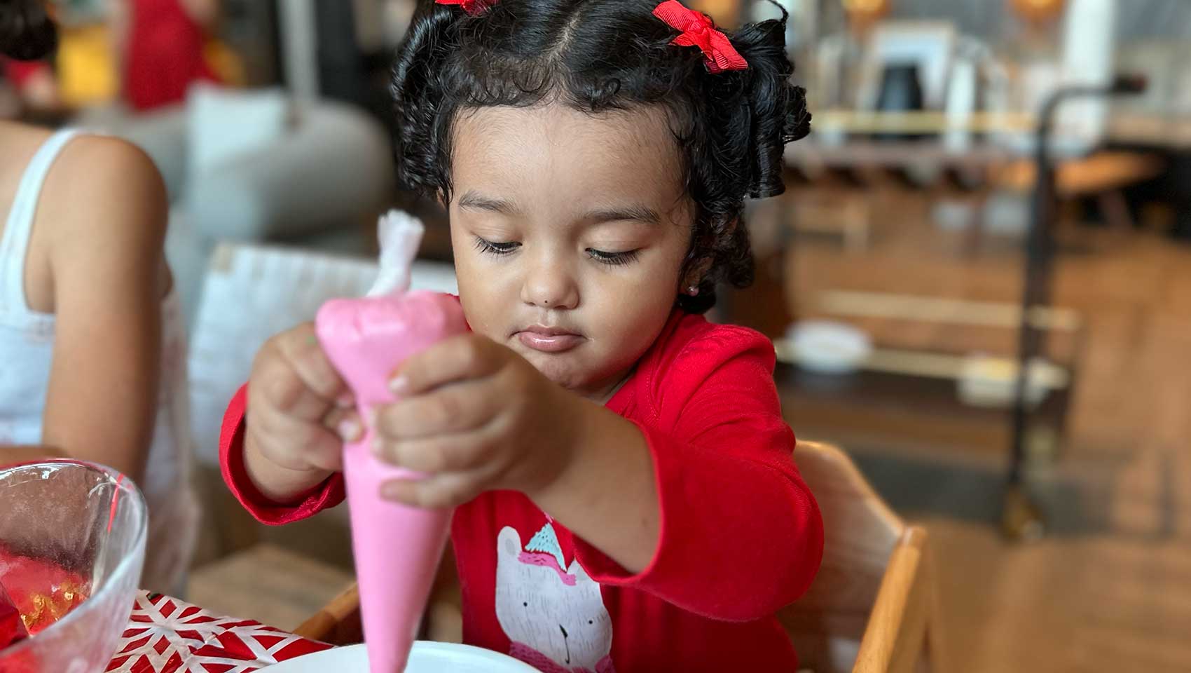 little girl decorates Christmas cookies with frosting