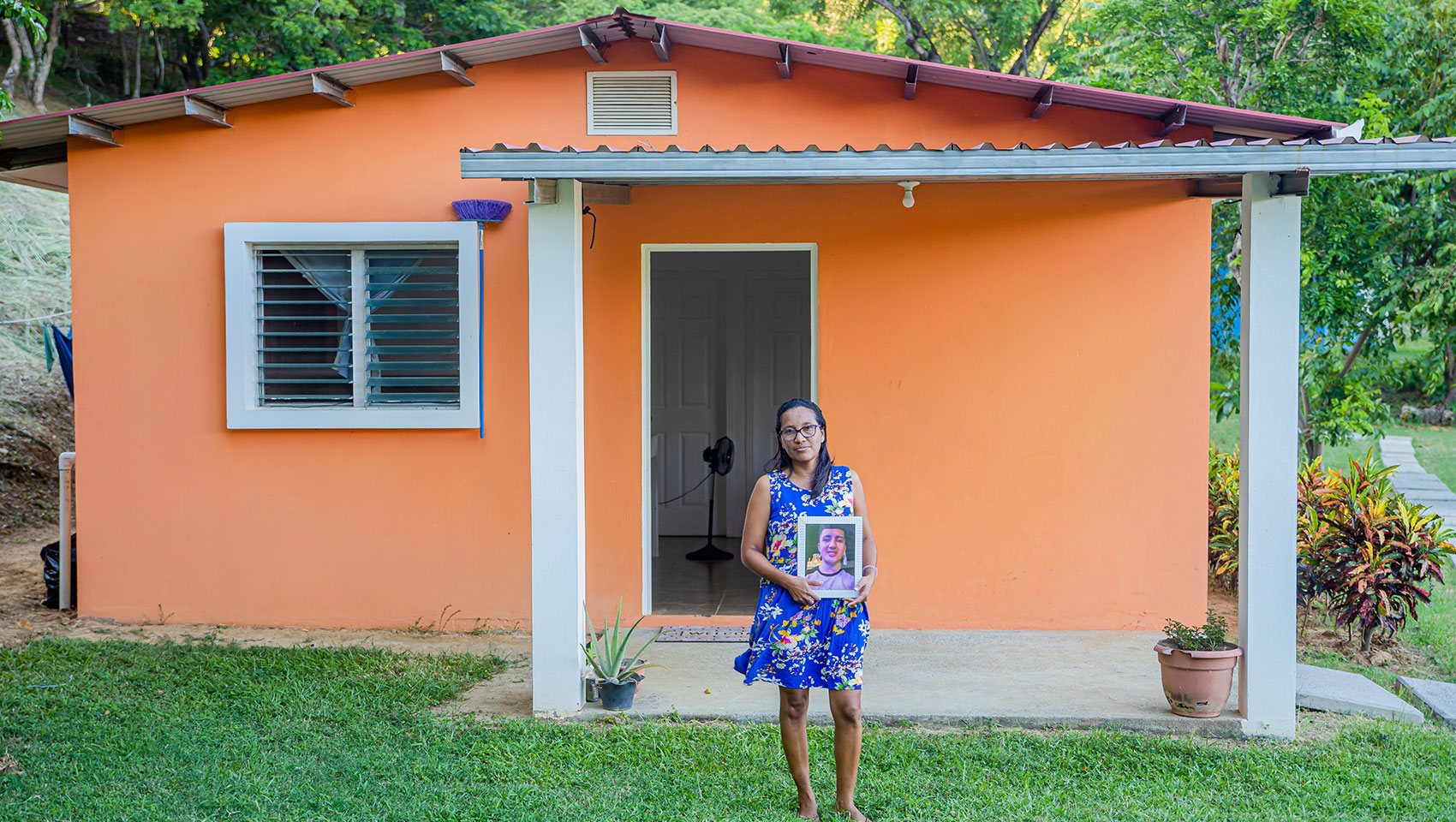 Woman in front of house with photo of kid