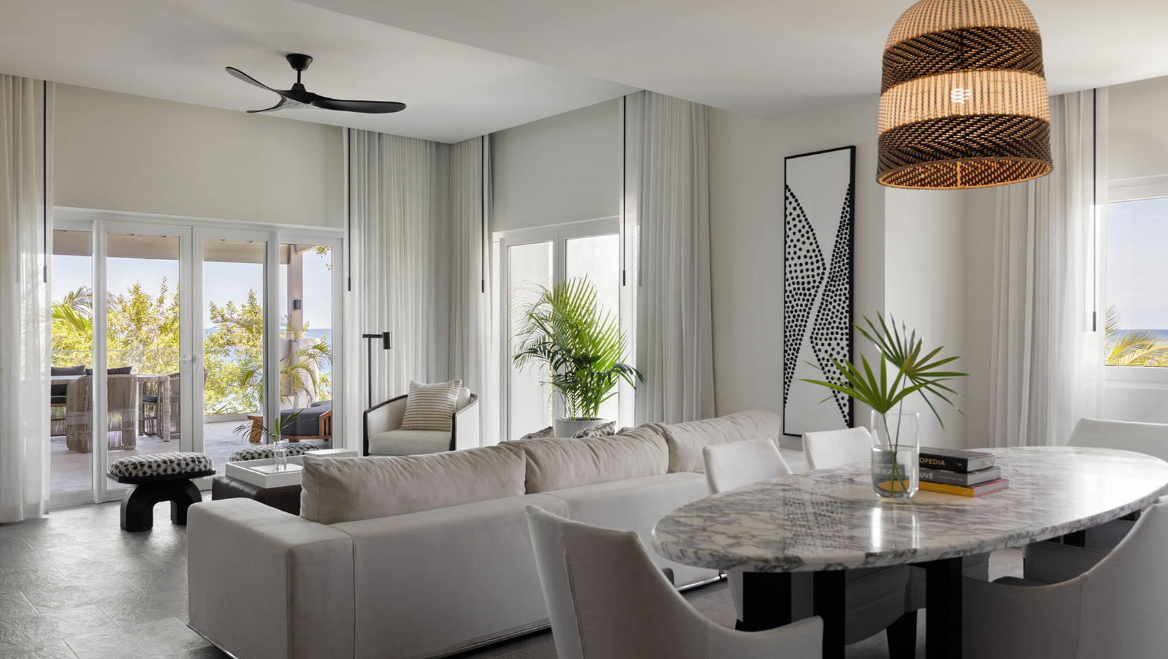 Living room seating with view of dining table and balcony in One Bedroom Premium Villa Suite Beachfront at Kimpton Grand Roatan Resort