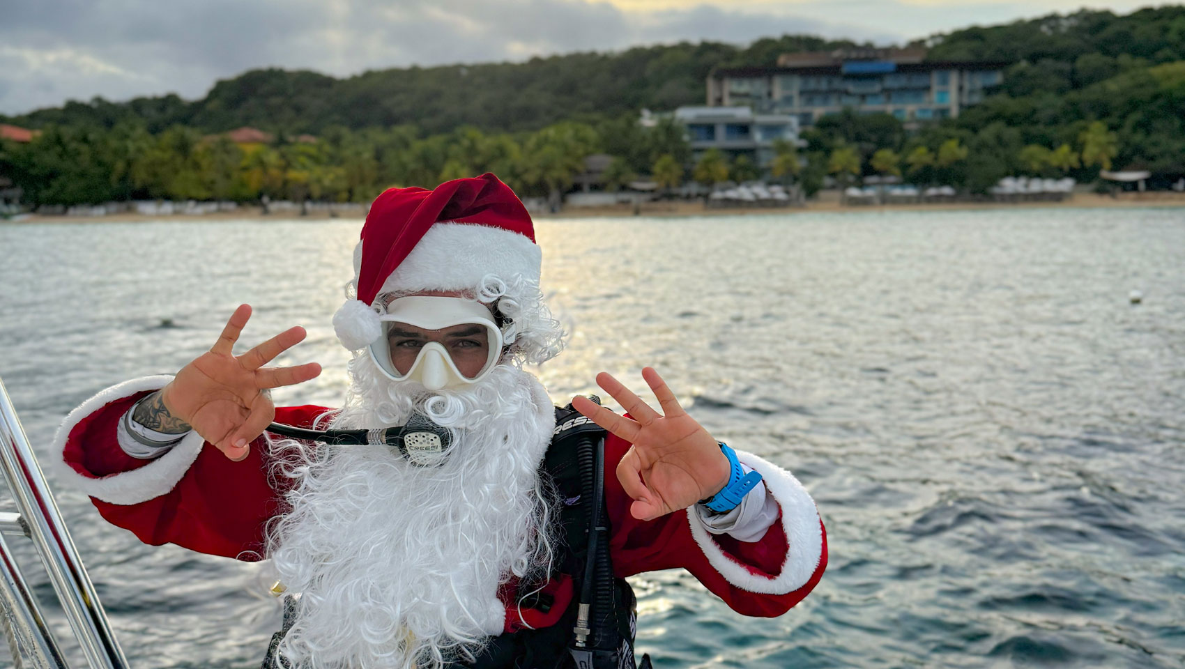 Santa Clause on a boat with Kimpton Grand Roatan in the background