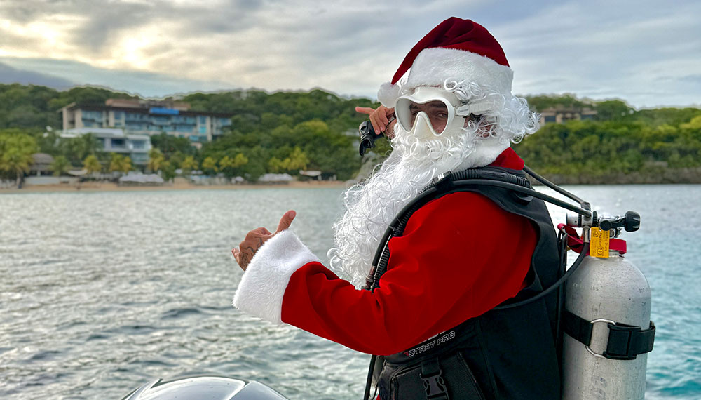 Santa on a boat with Kimpton Grand Roatan in the background
