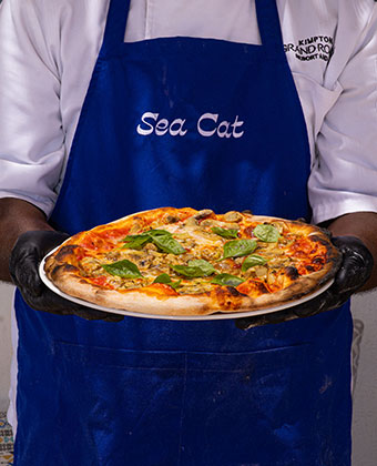 man in sea cat apron holding a pizza
