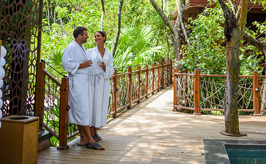 Couple in robes holding Champagne poolside at Kimpton Grand Roatan