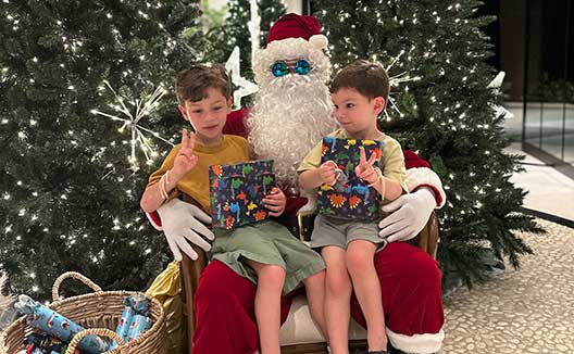 two boys sit on <q>santa’s</q> lap at Kimpton Grand Roatan Resort