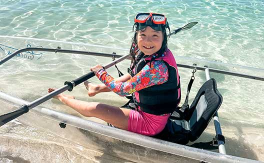 Girl in snorkel gear with clear bottom boat