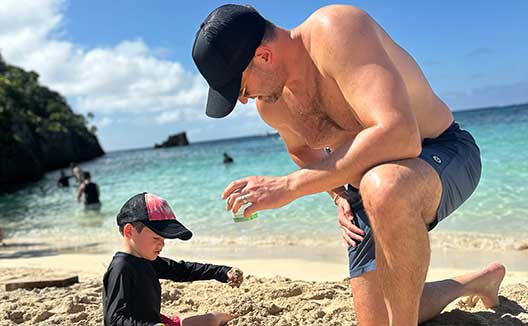 dad and son on beach playing with sand